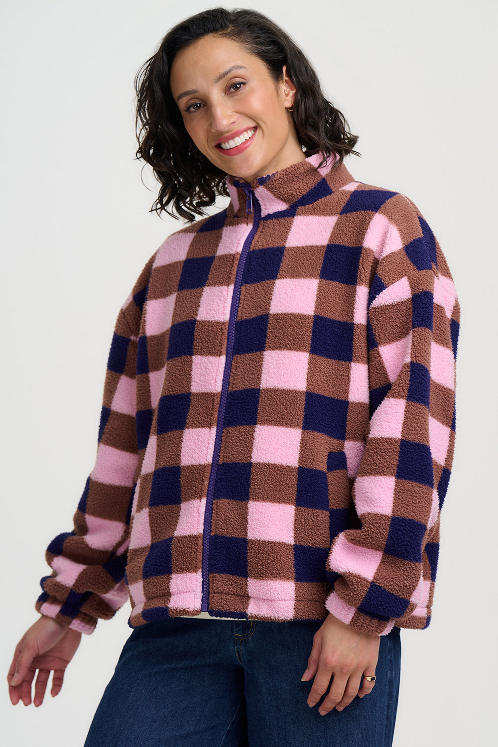 Woman wearing a checkered jacket with pink and brown pattern on a white background