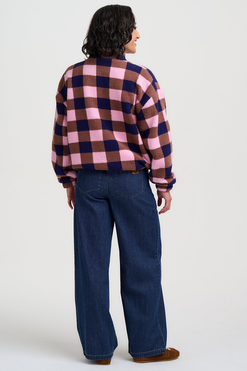Person wearing a checkered shirt and jeans on a white background
