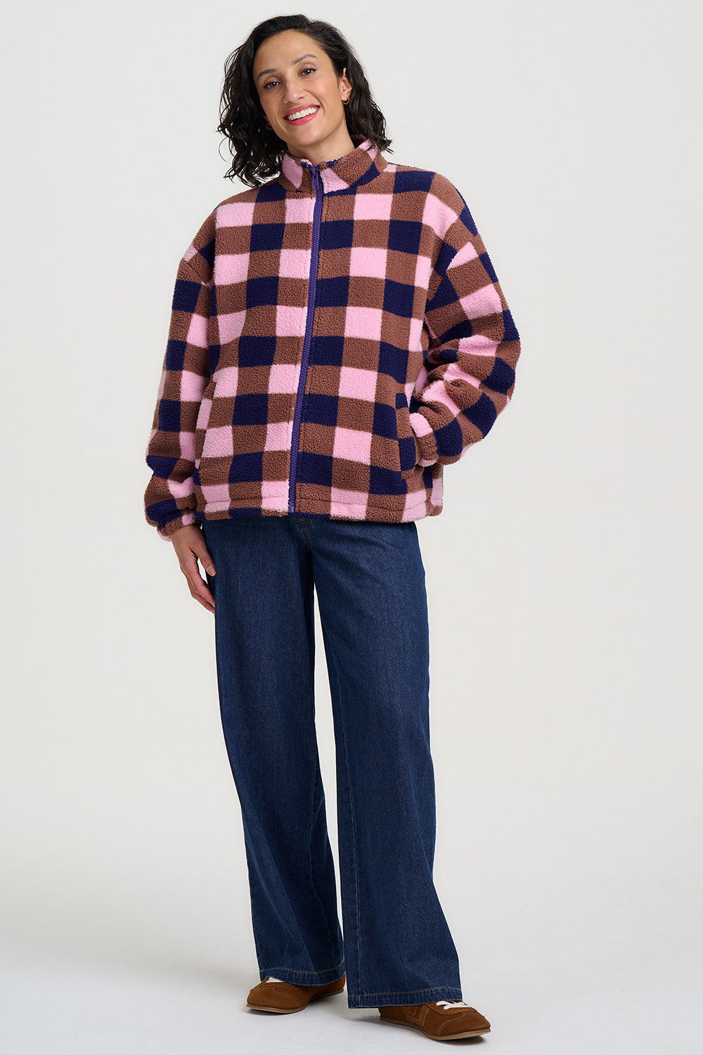 Person wearing a plaid shirt and blue pants on a white background