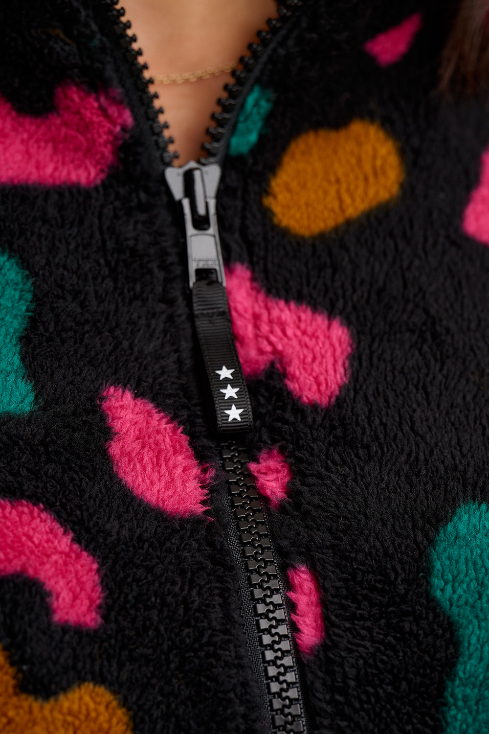 Close-up of a black zip-up hoodie with colorful abstract patterns.