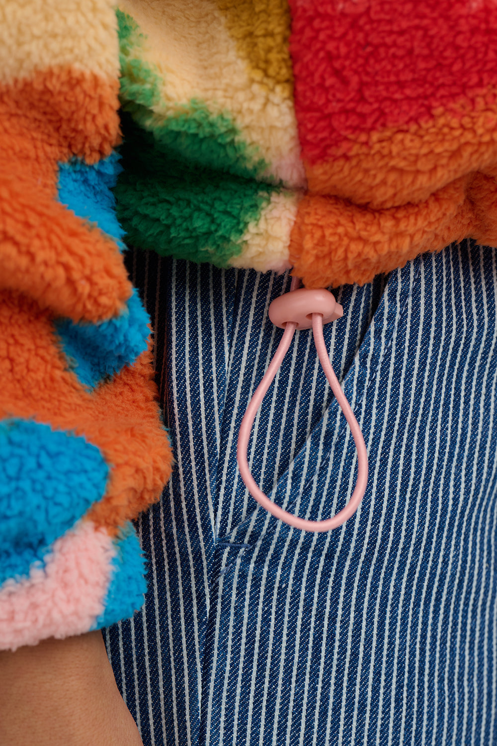 Close-up of colorful fleece jacket with a pink lanyard hanging out of a pocket.