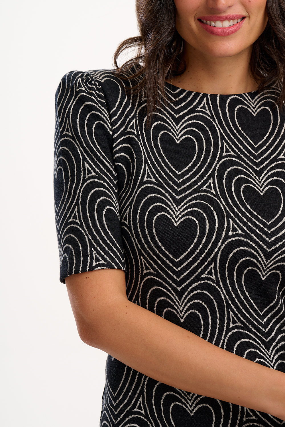 Woman wearing a black dress with white heart pattern on a plain background