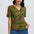 Woman wearing a green patterned blouse with blue pants on a white background