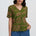 Woman wearing a green patterned blouse with blue pants on a white background
