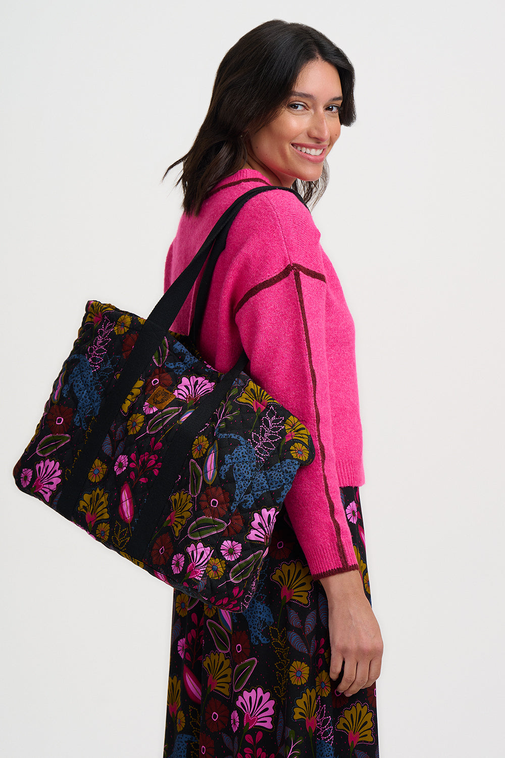 Woman holding a colorful floral-patterned bag against a white background