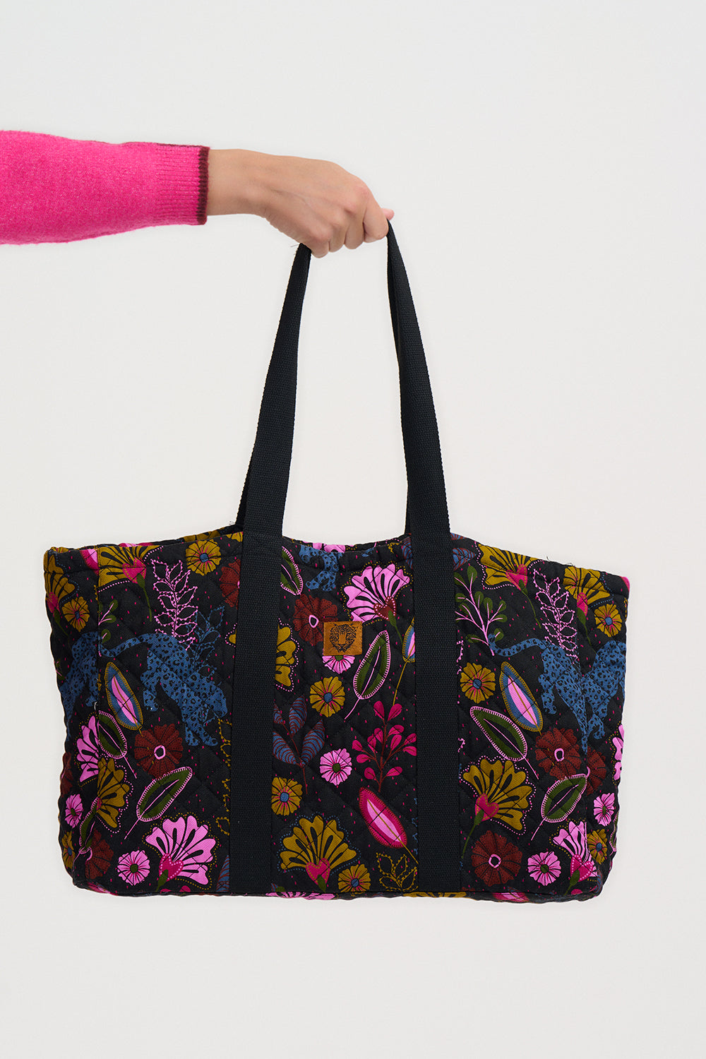 Tote bag with floral pattern held by a person against a white background