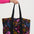 Tote bag with floral pattern held by a person against a white background