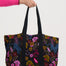 Tote bag with floral pattern held by a person against a white background