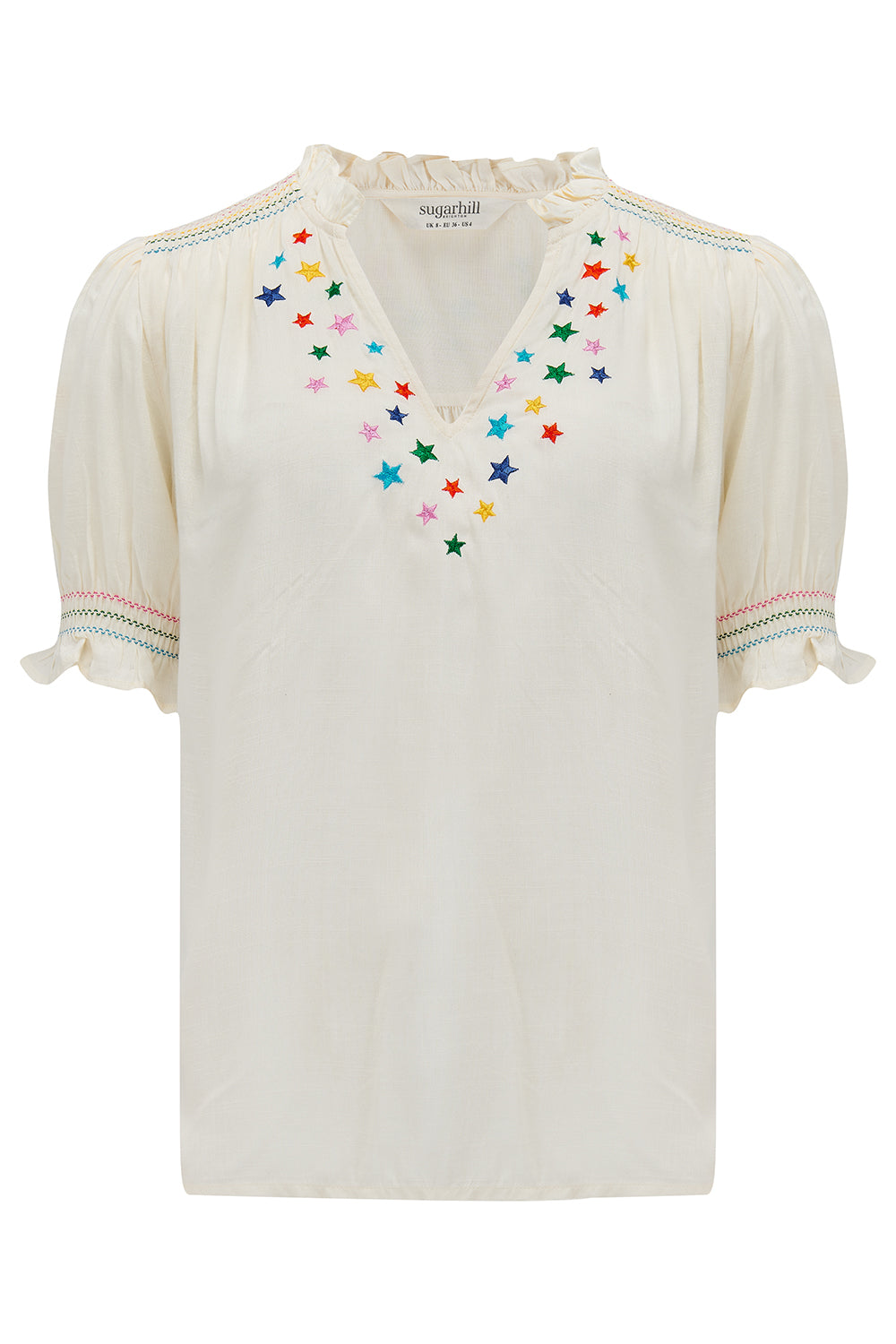 An off-white blouse with rainbow star embroidery around the neckline and on the sleeves, featuring a shirred frill cuff and a V-neckline.