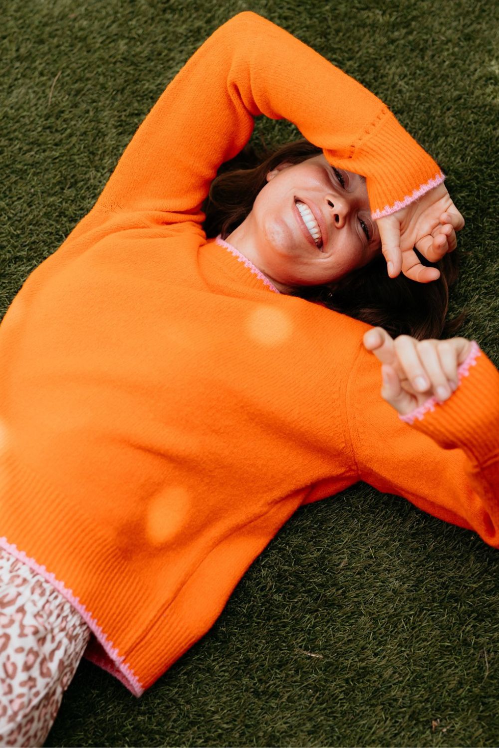 Person wearing an orange sweater lying on grass