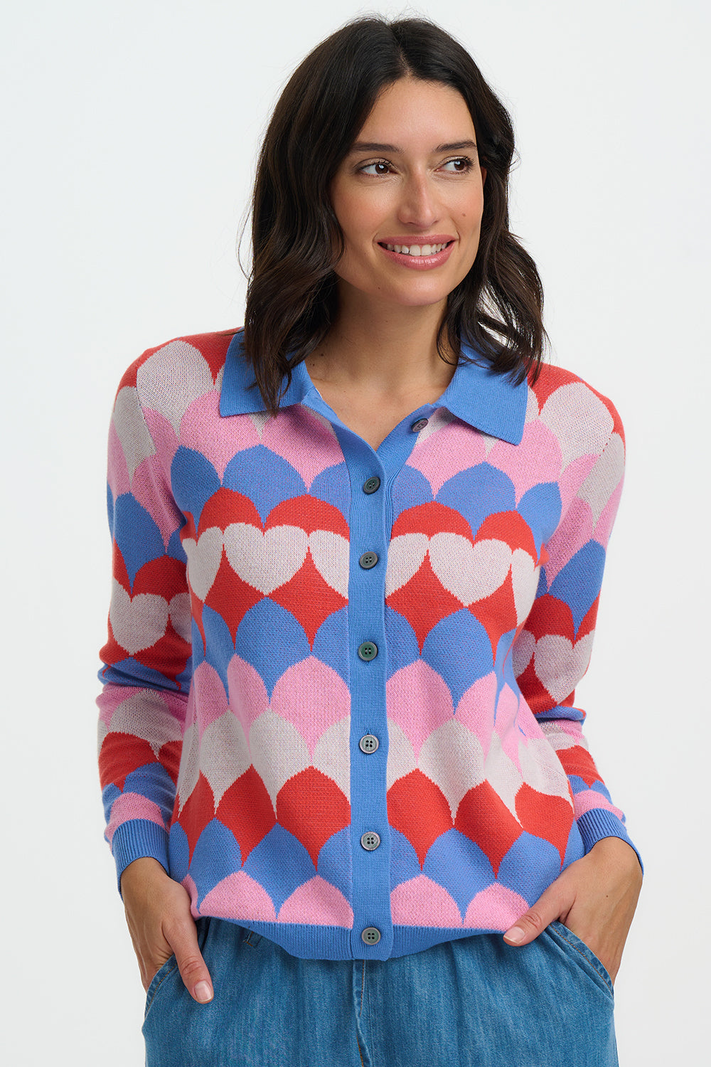 Woman wearing a colorful heart-patterned cardigan on a white background