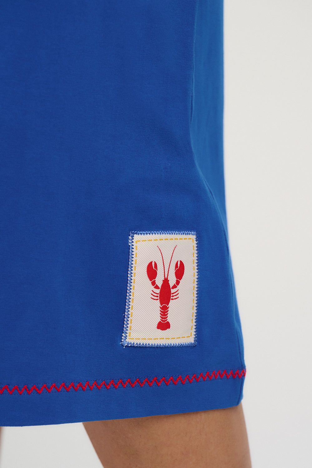 Blue garment with a red and white lobster logo on a white background