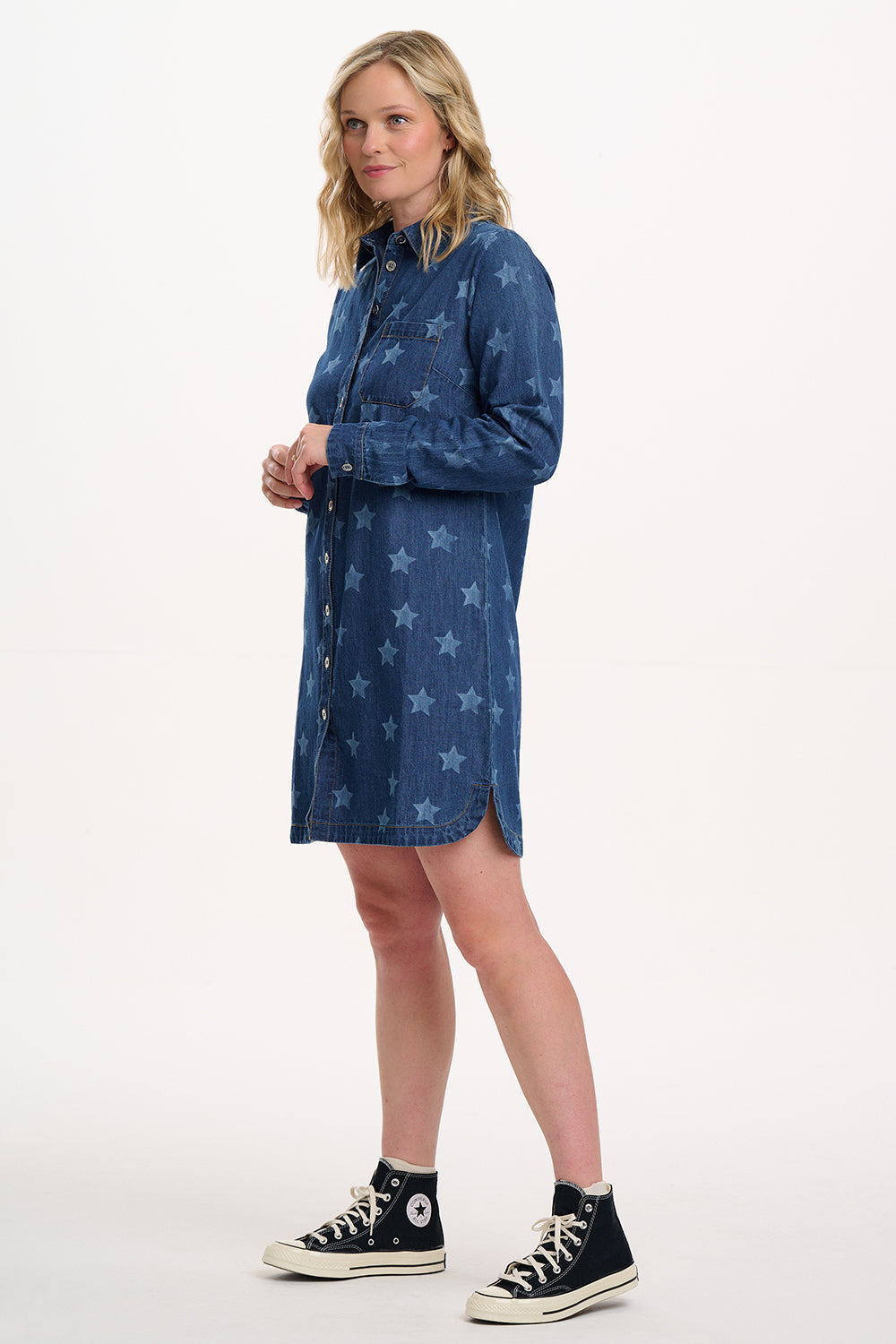 Woman wearing a blue denim dress with star patterns on a white background