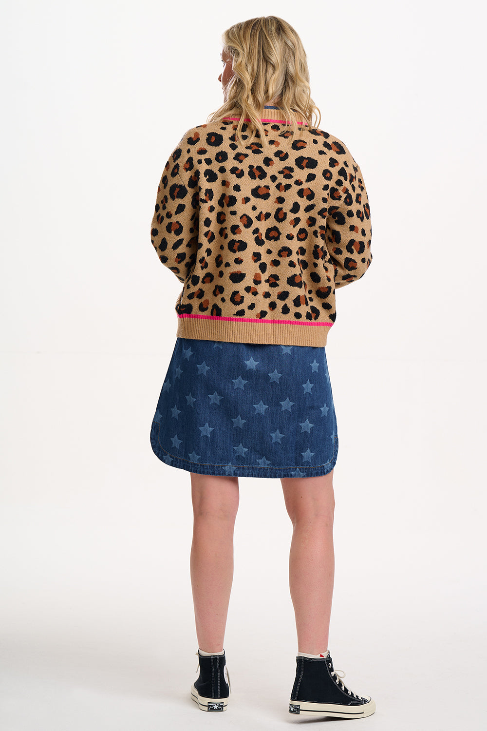 Person wearing a leopard print jacket and denim skirt on a white background