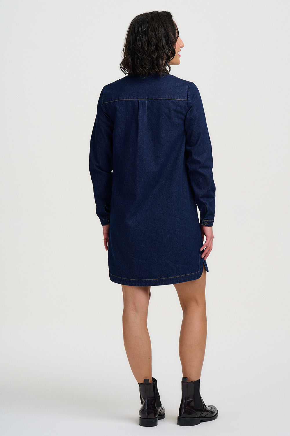 Person wearing a navy blue dress with long sleeves on a white background