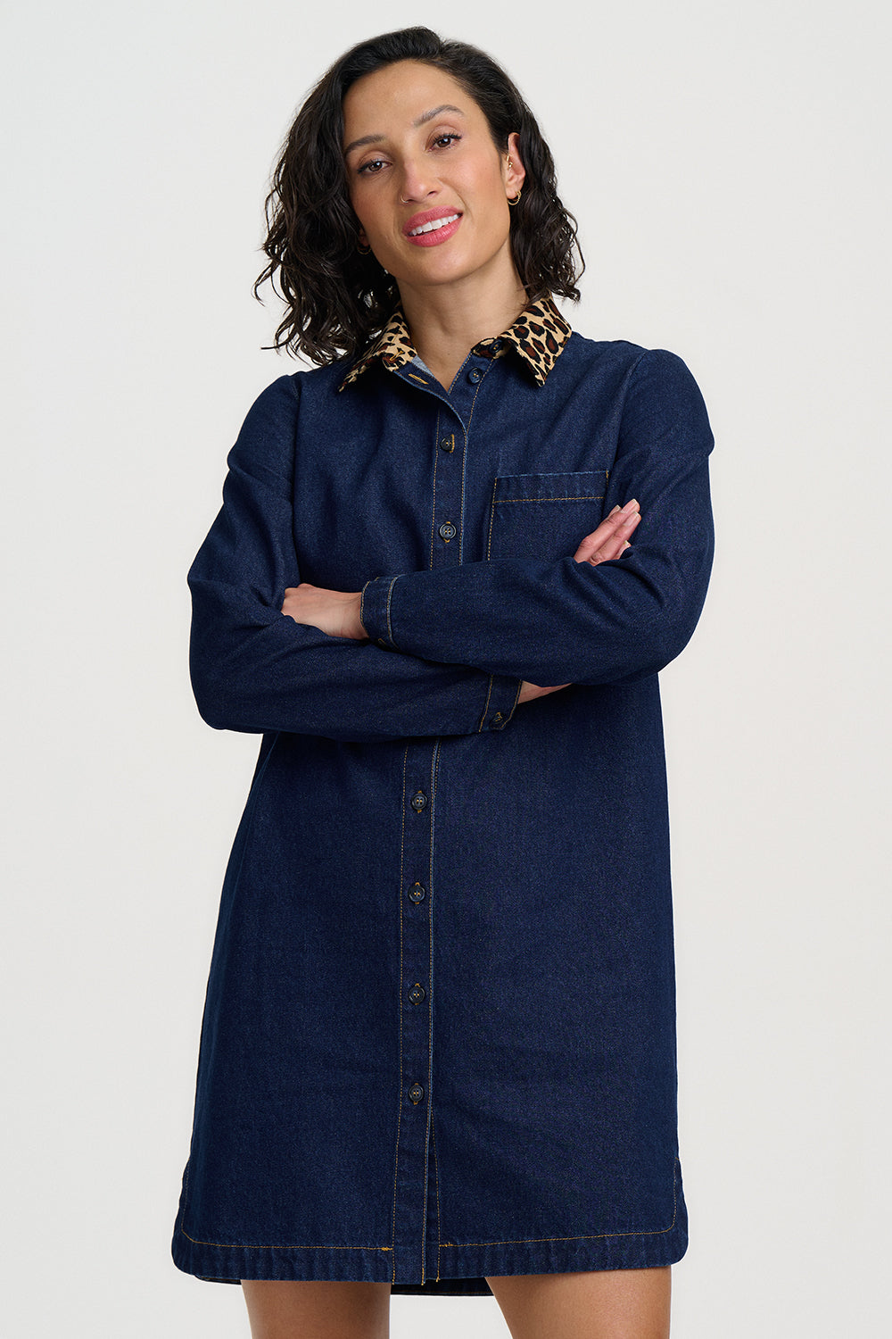 Woman wearing a navy denim dress with a white background