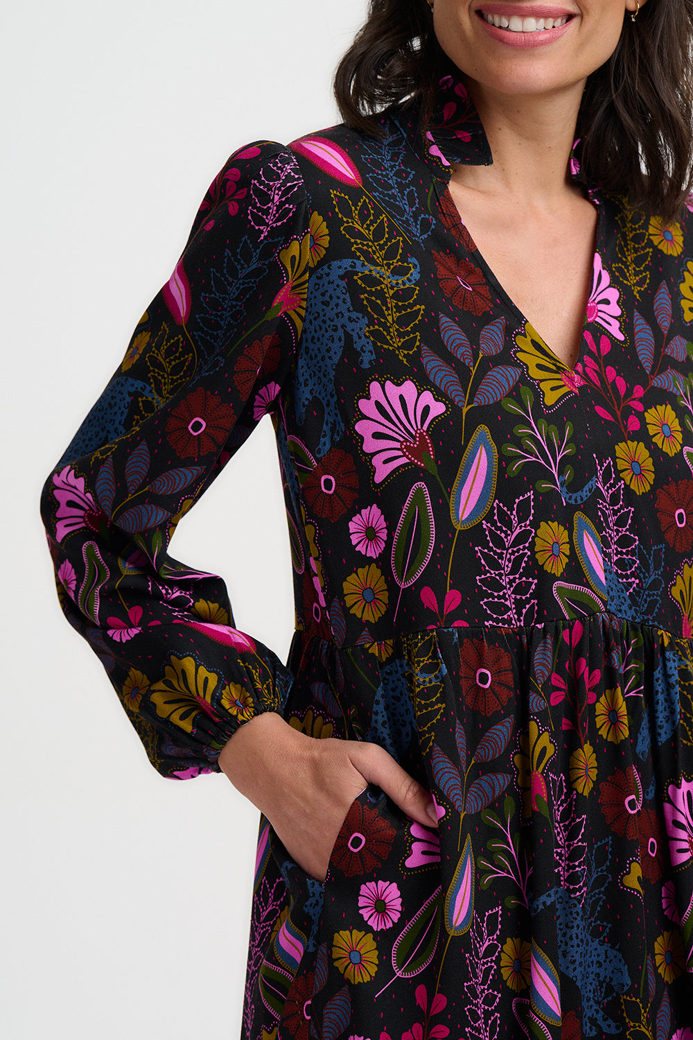 Woman wearing a long-sleeve dress with a colorful floral pattern on a white background