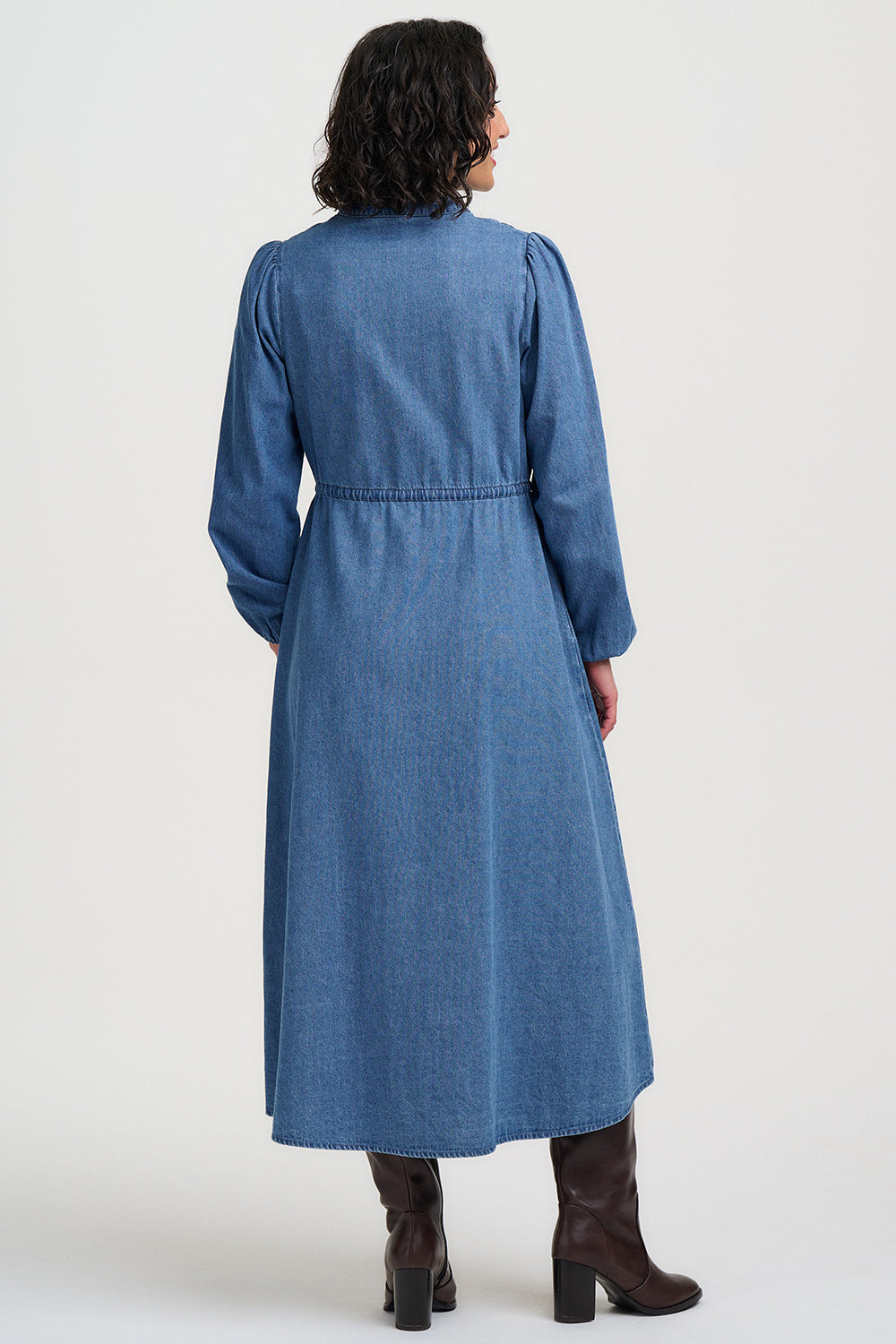 Woman wearing a blue denim dress with a belt on a white background