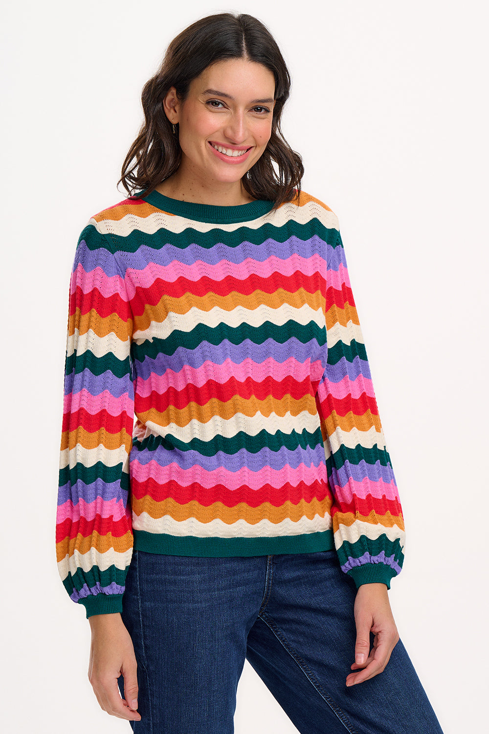 A woman wearing a multicolored striped jumper with a round neckline and long sleeves.