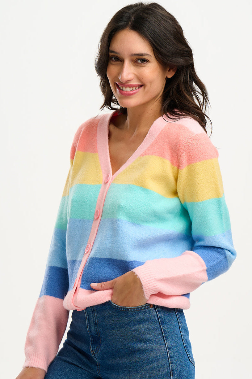 A woman wearing a multicolored striped cardigan with a deep v neckline and large buttons, in pastel colors such as pink, yellow, blue, and green.