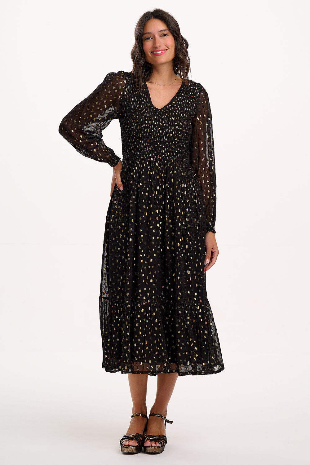 Woman wearing a black dress with gold polka dots on a white background