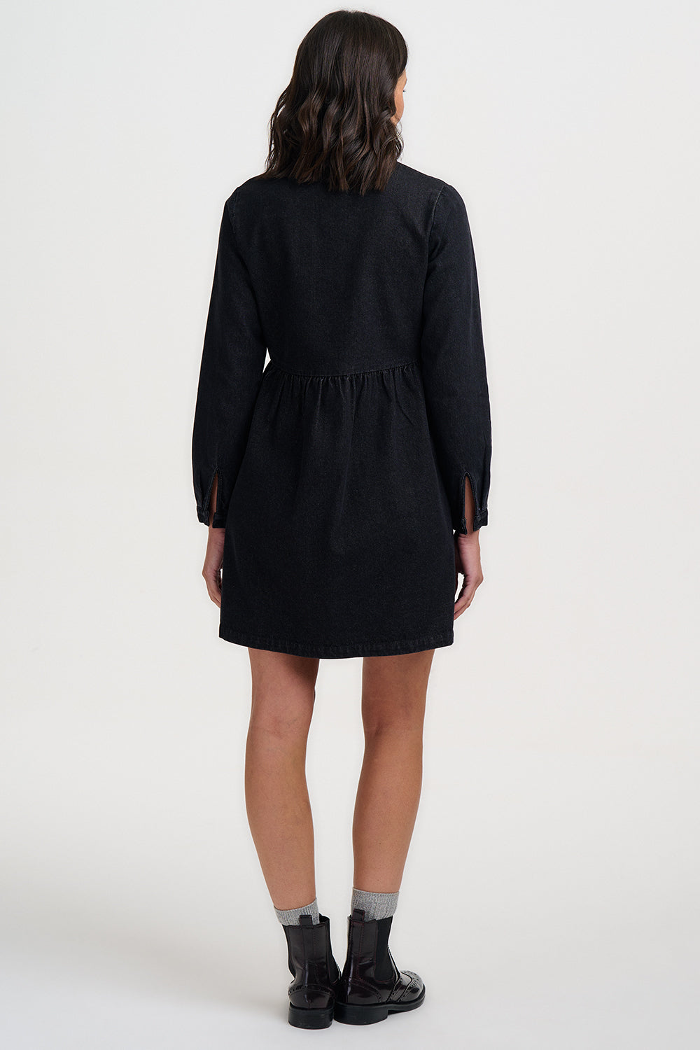 Person wearing a black dress with long sleeves on a white background