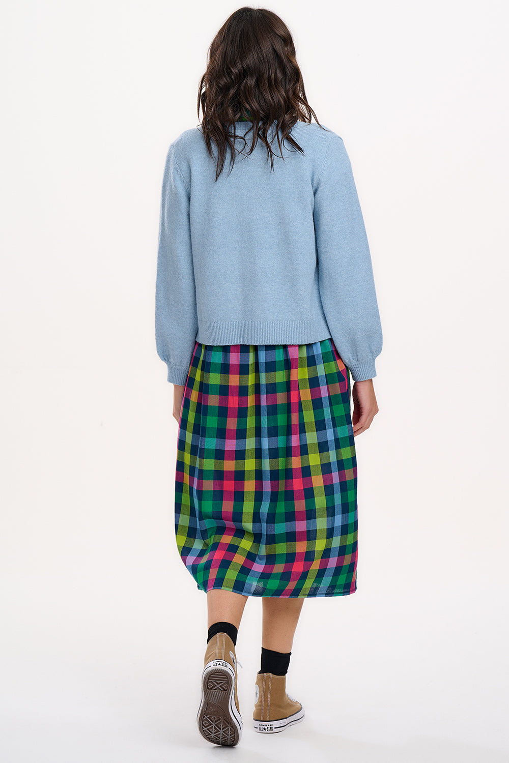 A woman wearing a sky blue Jamie Cardigan with ribbed round neck, buttoned front, and blouson sleeve. The cardigan features small matching sky blue buttons with accent hot pink stitching.