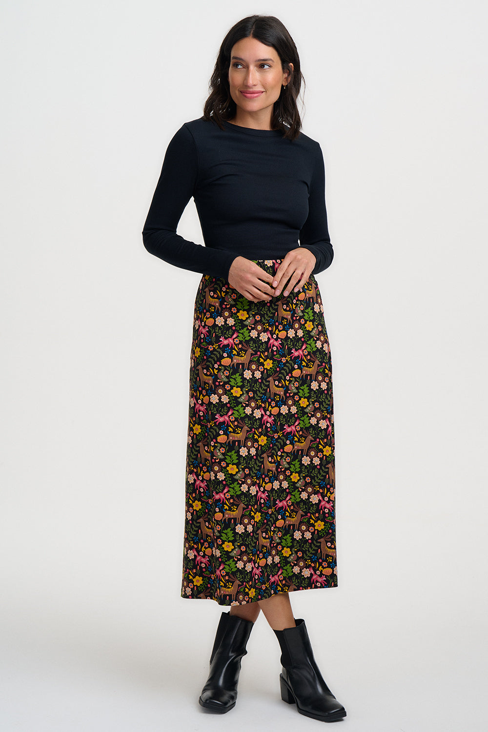 Woman wearing a black long-sleeve top and a floral skirt on a white background