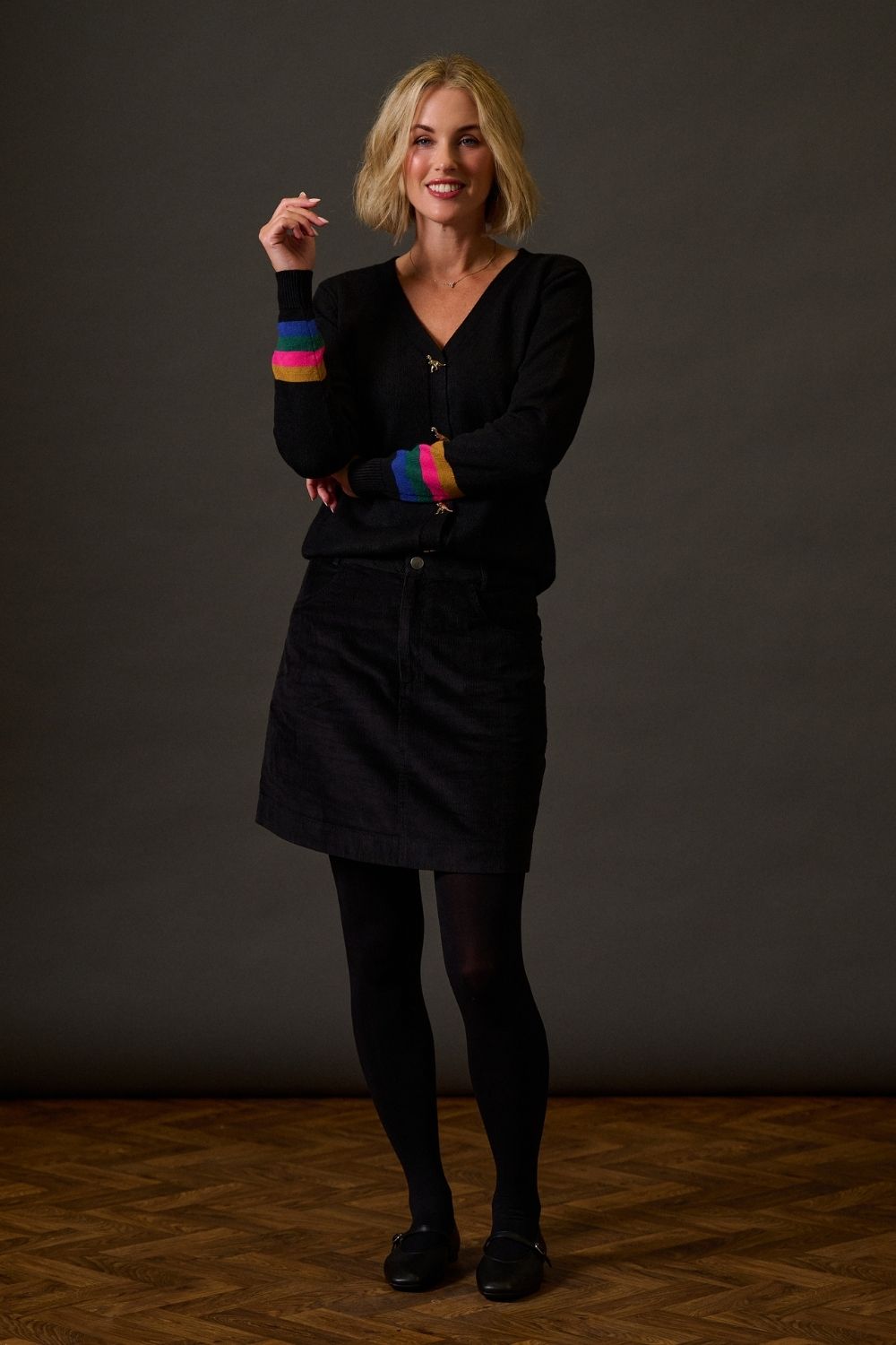 Woman wearing a black outfit with colorful sleeves against a dark background
