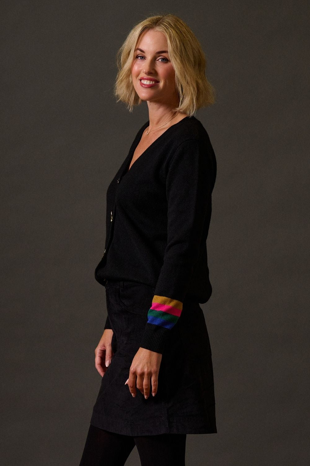 Woman wearing a black outfit with colorful cuffs on a dark background