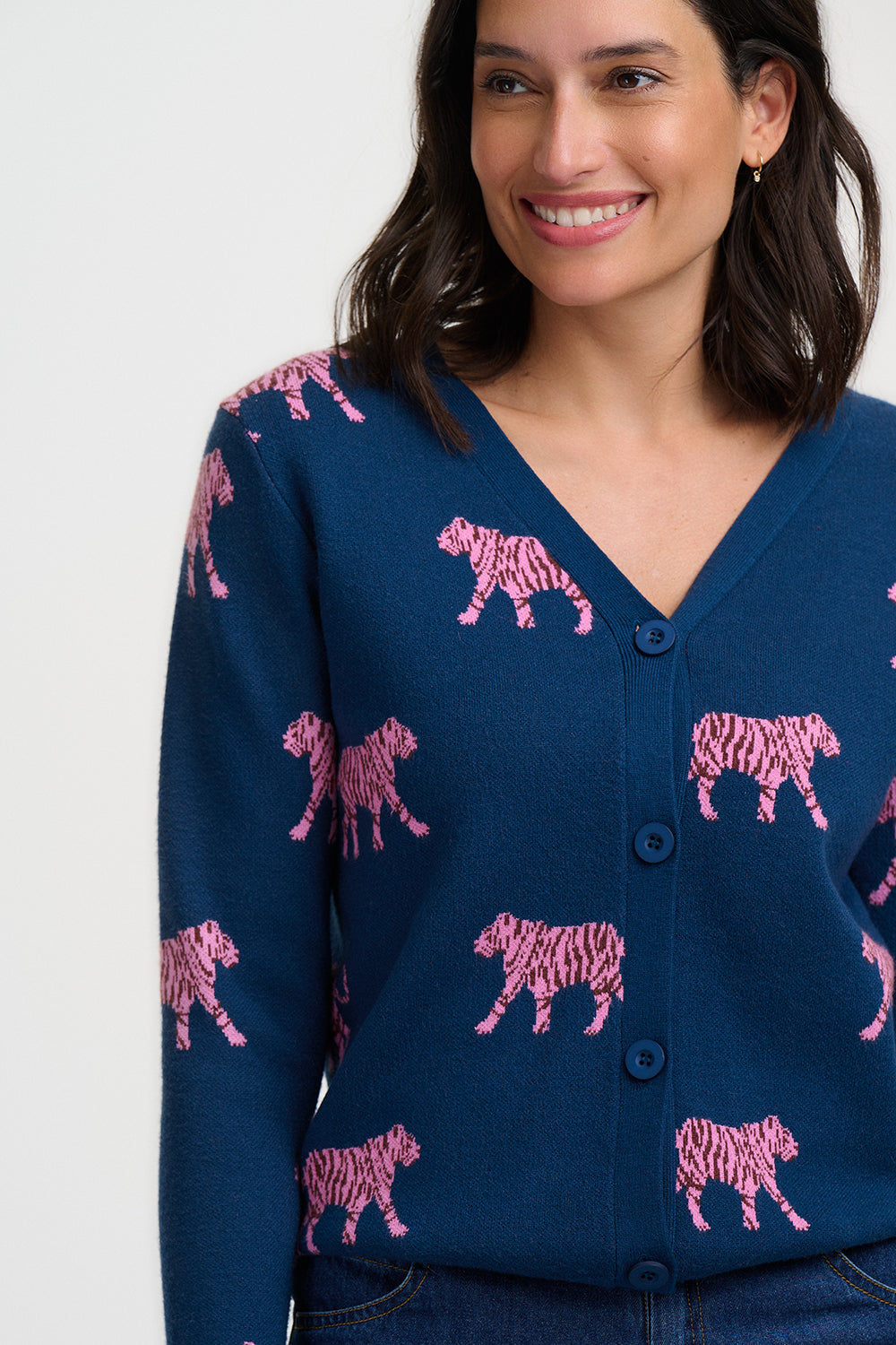 Woman wearing a navy blue cardigan with pink zebra patterns on a plain background