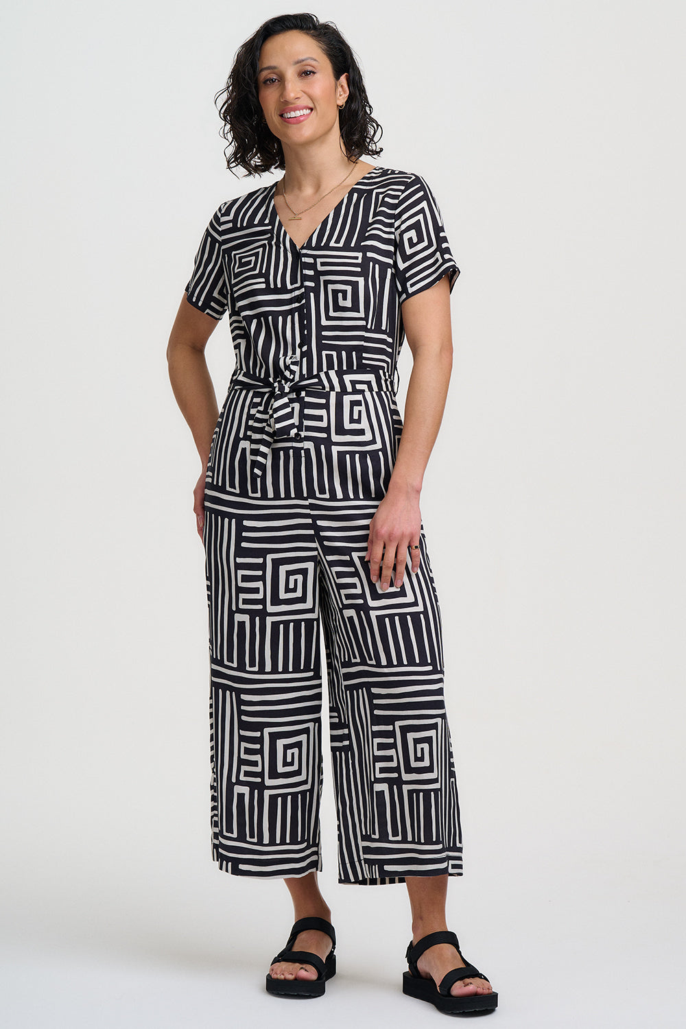 Woman wearing a black and white geometric patterned jumpsuit on a white background