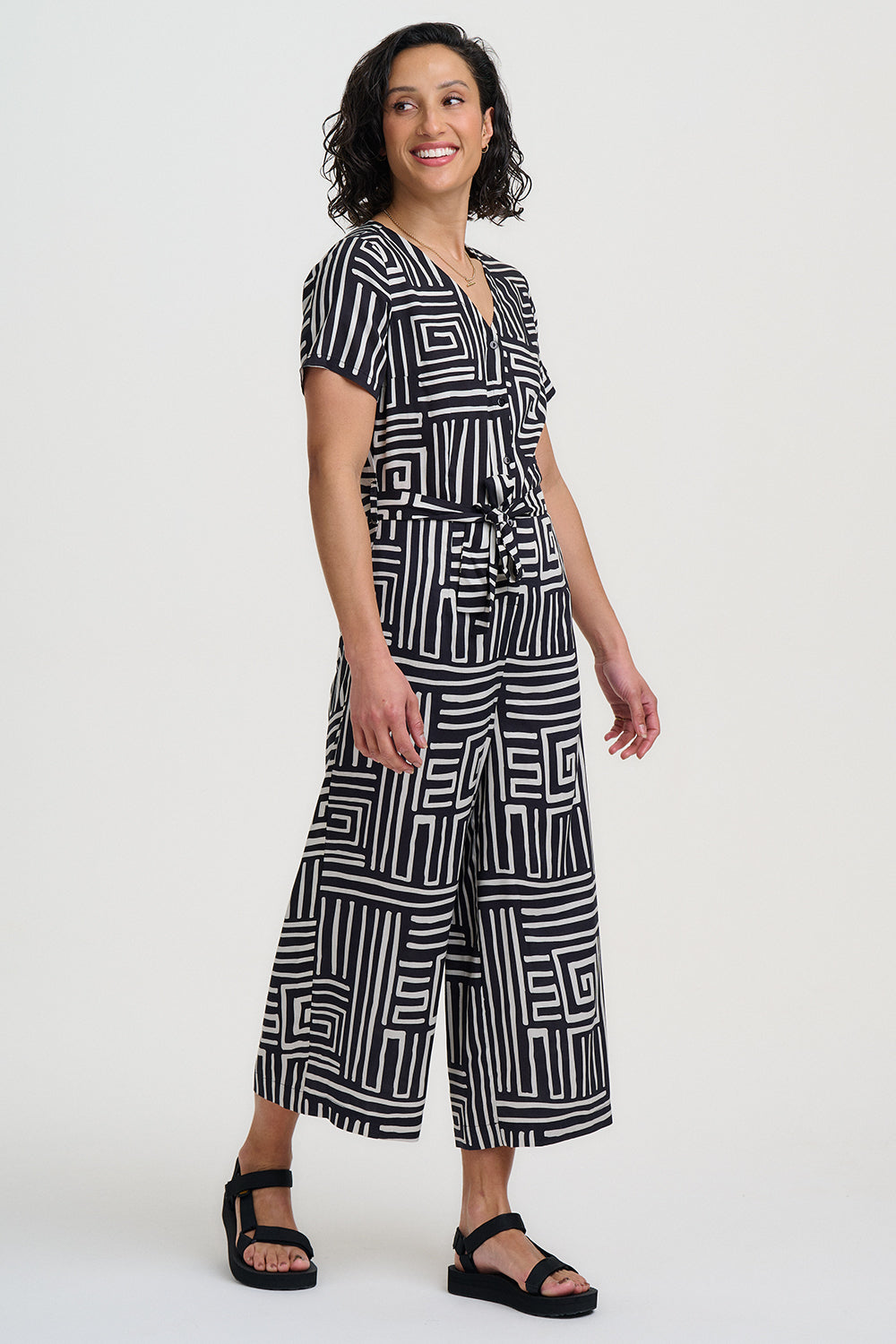 Woman wearing a black and white geometric patterned jumpsuit on a white background