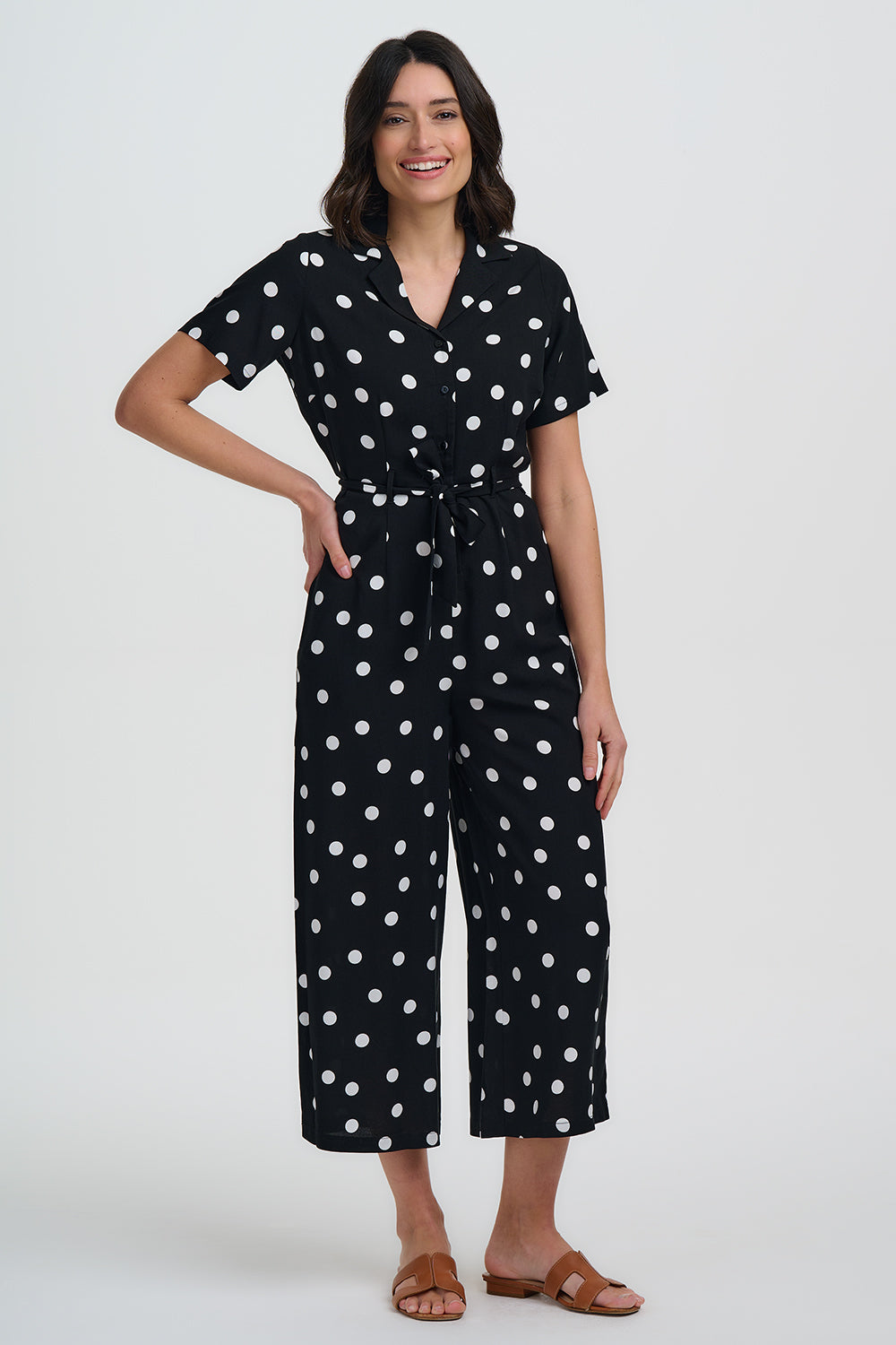 Woman wearing a black polka dot jumpsuit on a white background