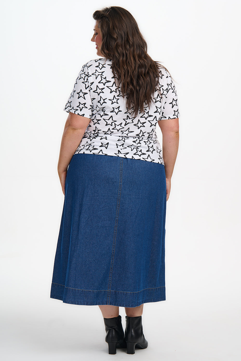 Woman wearing a white blouse with black butterfly pattern and a blue denim skirt on a white background