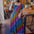 Woman in a colorful dress drinking from a green cup in a cafe.
