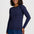 A woman modeling a navy blue long-sleeve knit top with a purple geometric pattern, paired with a blue denim skirt, against a light gray studio background.