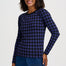 A woman modeling a navy blue long-sleeve knit top with a purple geometric pattern, paired with a blue denim skirt, against a light gray studio background.