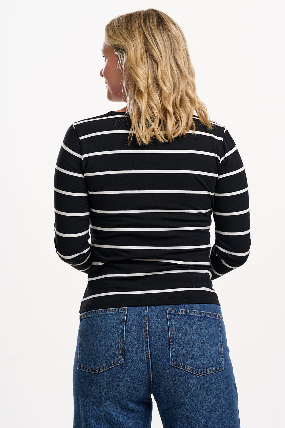 Sugarhill brighton model wearing a black and white striped sweater and blue jeans on a white background