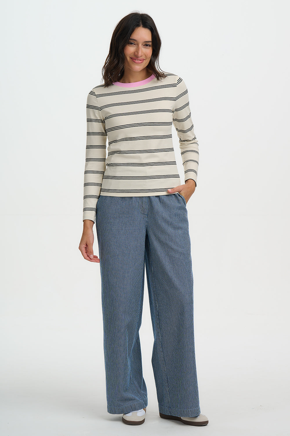 Woman wearing a striped sweater and blue pants on a white background