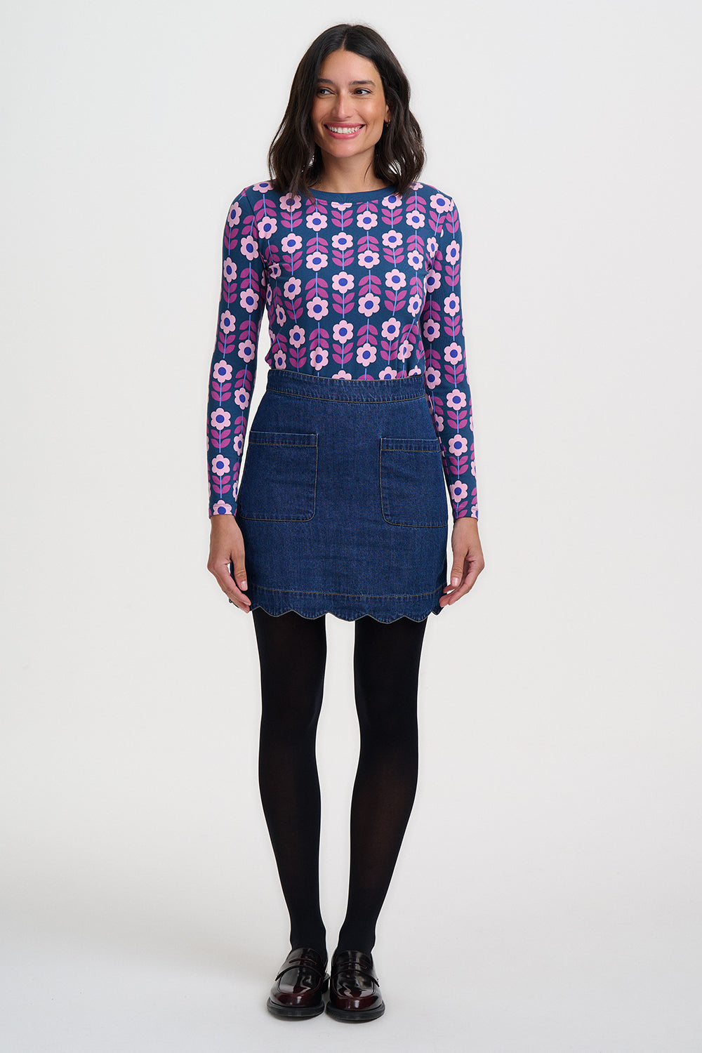 Woman wearing a patterned sweater and denim skirt on a white background
