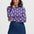 Woman wearing a floral patterned top and denim skirt on a white background