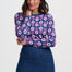 Woman wearing a floral patterned top and denim skirt on a white background