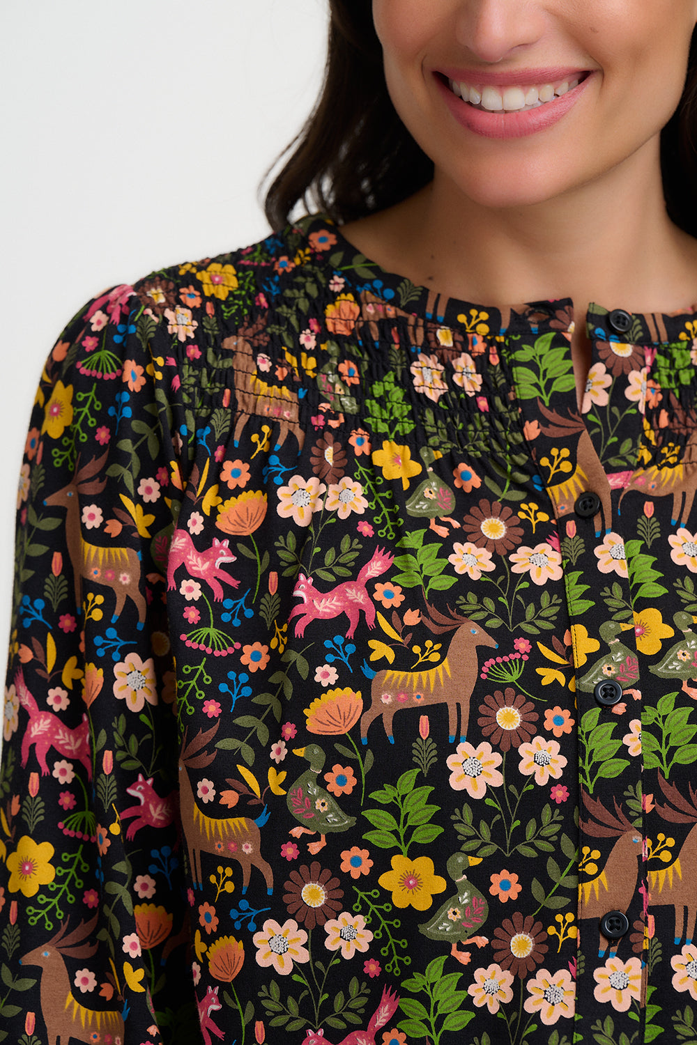 Woman wearing a dark dress with colorful floral and animal patterns on a white background