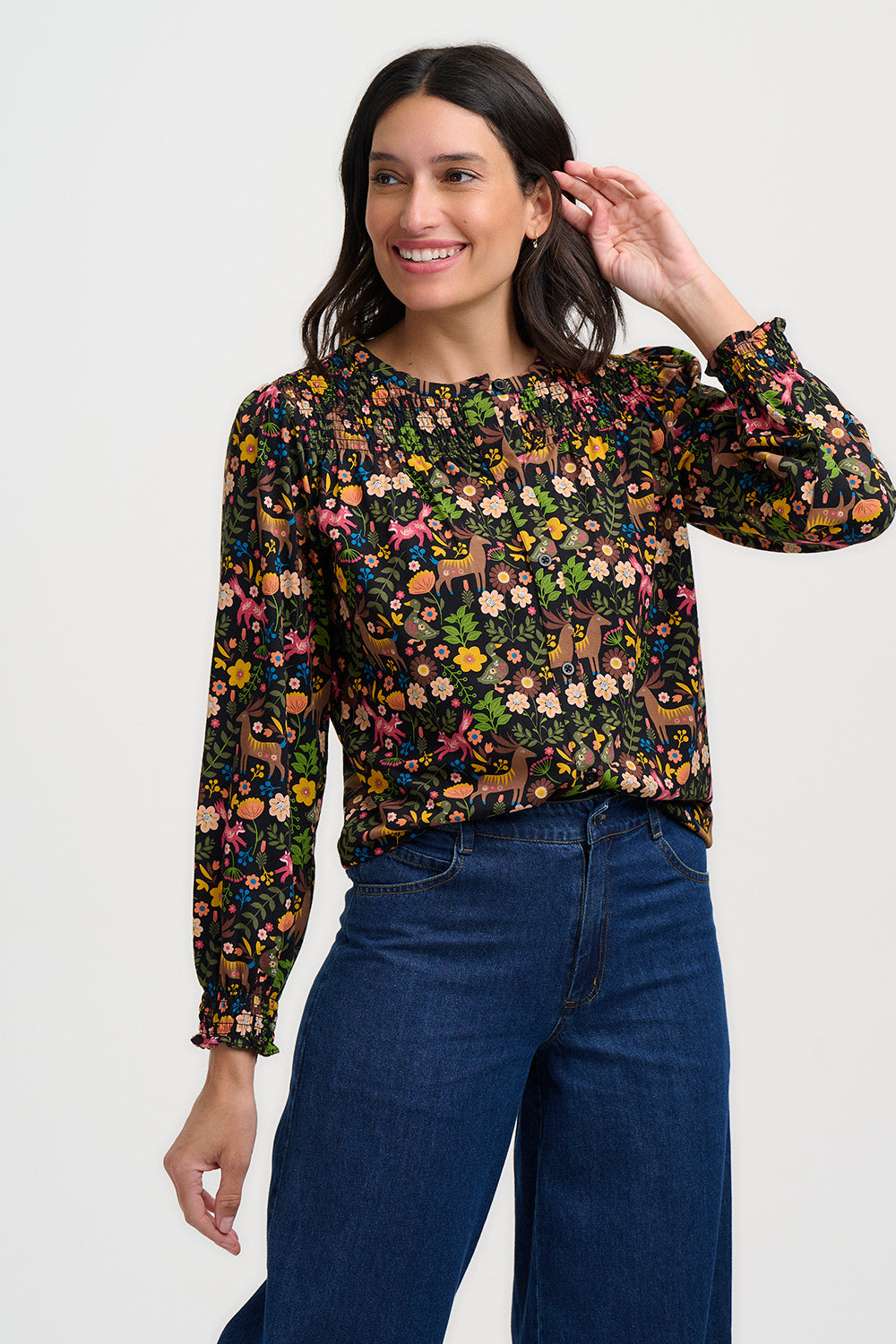 Woman wearing a colorful floral blouse and blue jeans on a white background