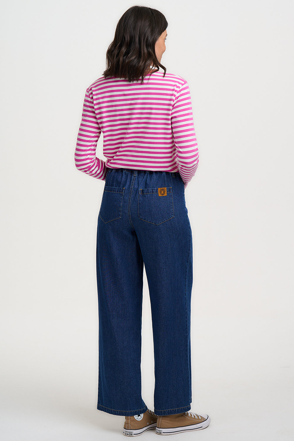 Person wearing a pink and white striped shirt and blue jeans on a white background