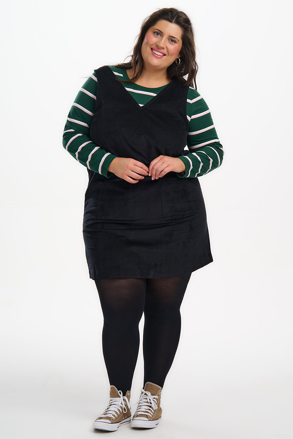 Woman wearing a black dress with green and white striped sleeves on a white background