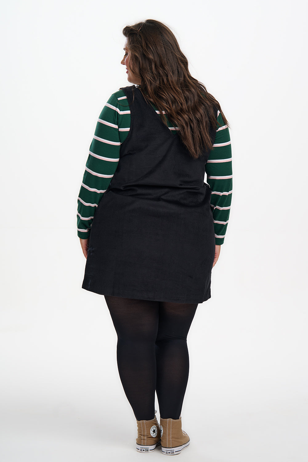 Person wearing a black dress with green and white striped sleeves on a white background