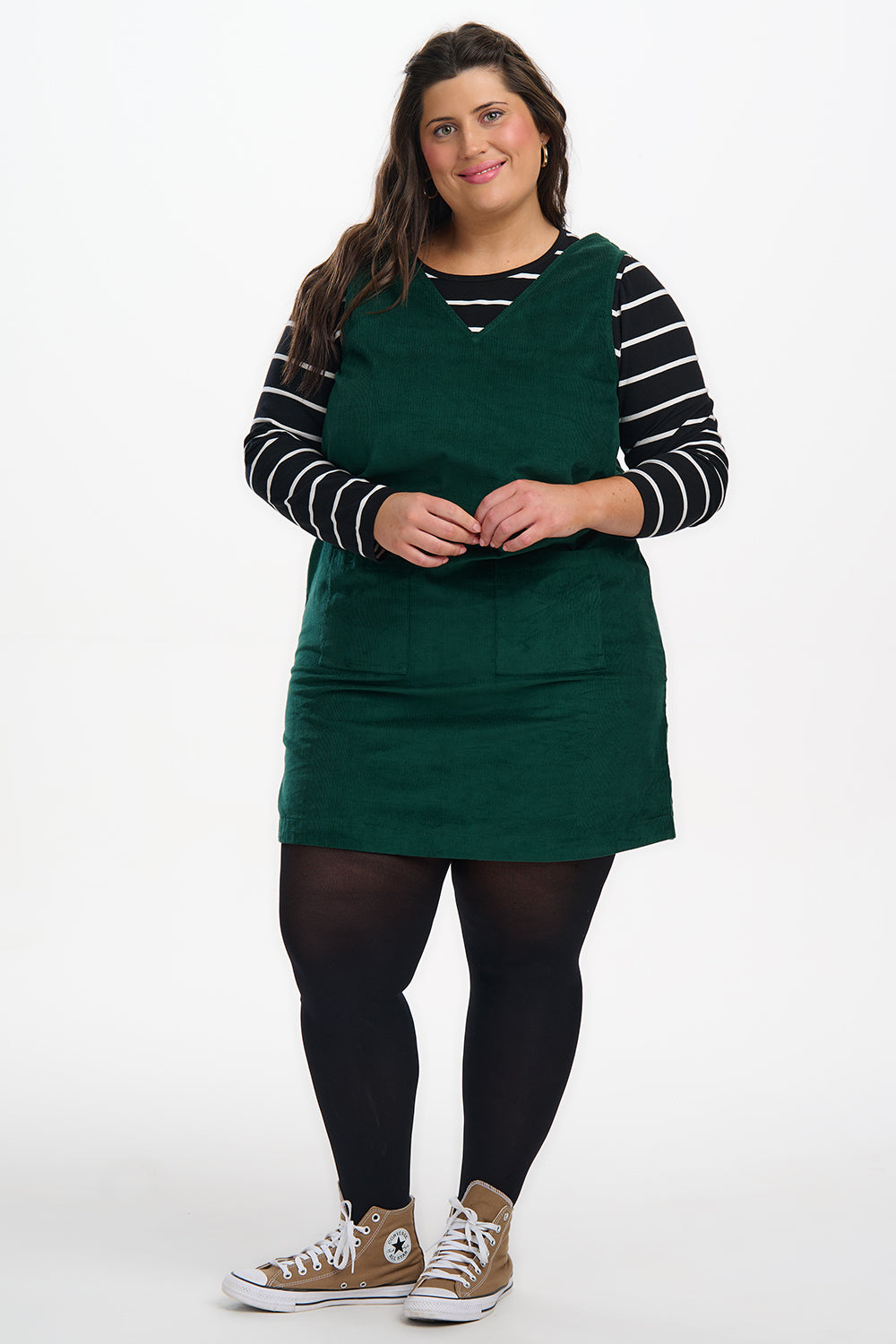 Person wearing a green dress over a striped shirt on a white background