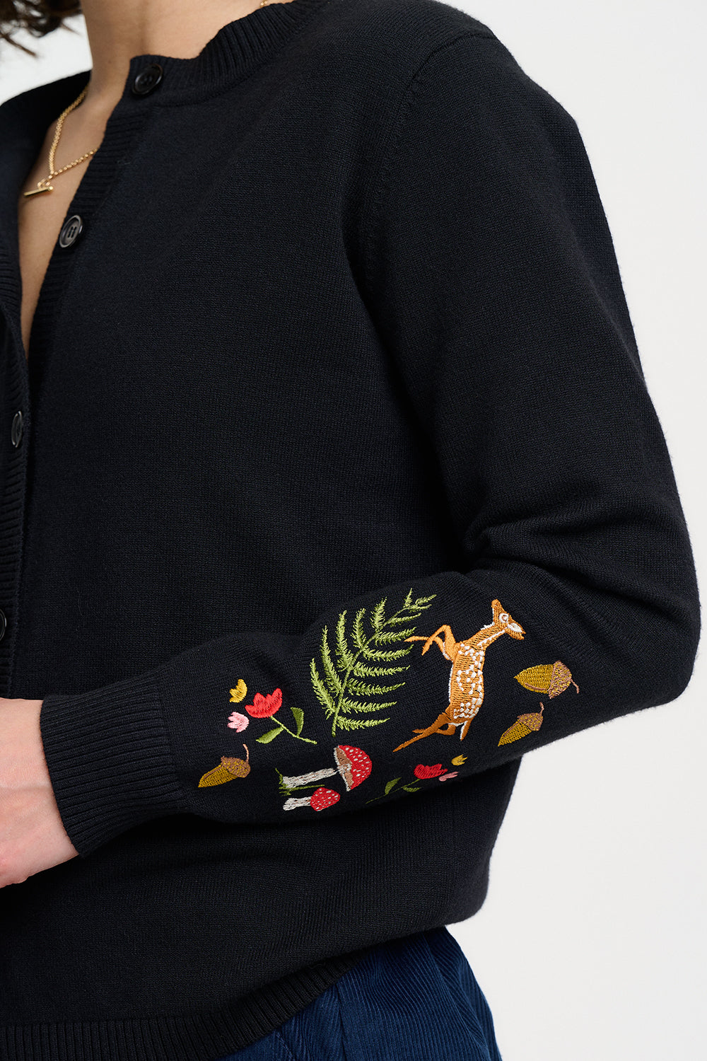 Black sweater with embroidered arm details on a white background